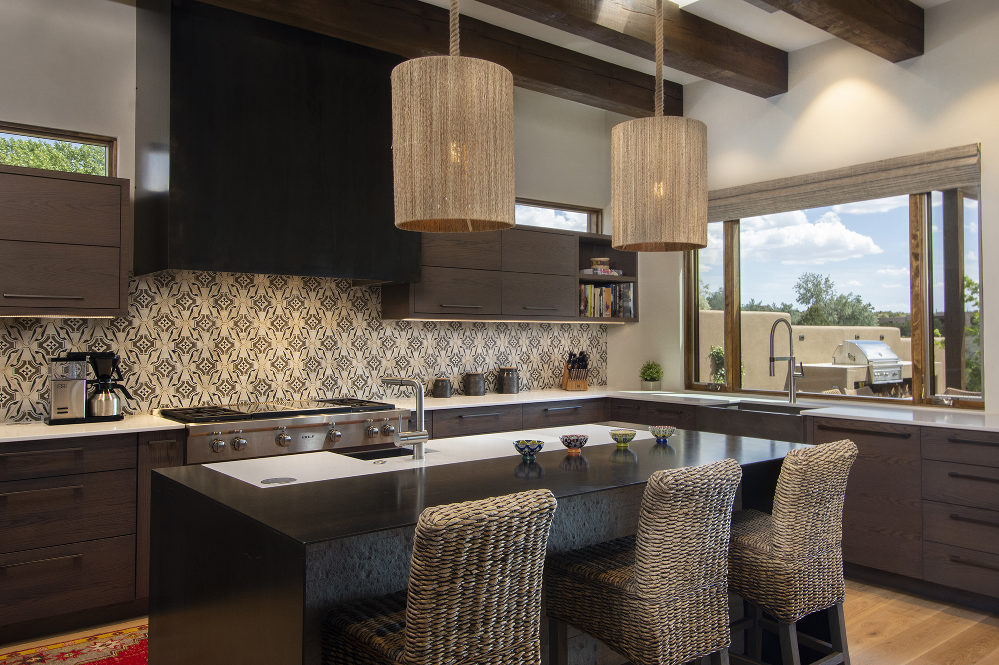 Custom Santa Fe kitchen with dark cabinetry, patterned tile backsplash, island seating and vigas