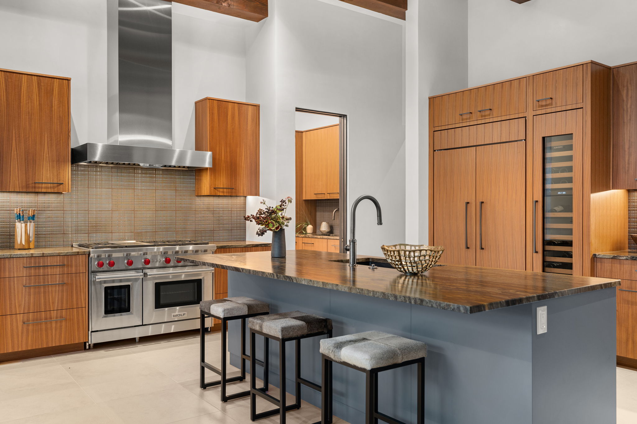 Contemporary custom kitchen with warm wood cabinetry, stone island and integrated appliances